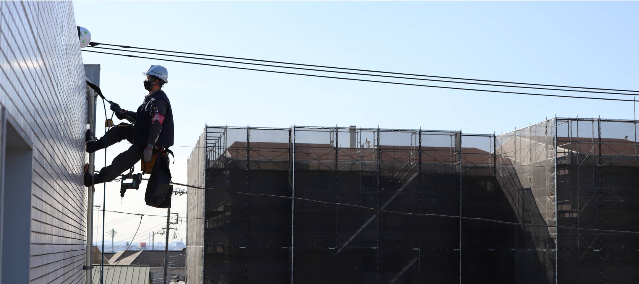 外壁に取り付けられたロープを使い、高所で作業する作業員。
